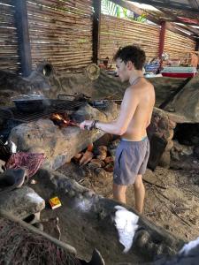 a man standing in front of a fire at Natural Suites ENSUEÑOS Natural Reserve in Little Corn Island