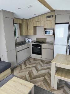 a kitchen with white cabinets and a wooden floor at Rosie Caravan Selsey in Selsey