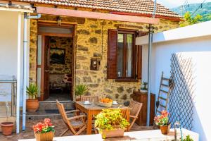 a house with a table and chairs on a patio at Pandora Stone Cottage Elos in Élos