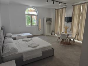 a white bedroom with two beds and a dining room at Melina Rooms in Dhërmi
