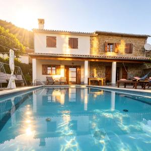 a villa with a swimming pool in front of a house at Kuća Zanetta sa bazenom in Buzet