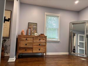 a dresser in a room with a mirror and a window at Eclectic & Fun Custom Home in Shawnee