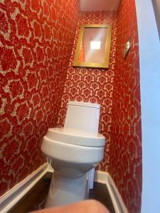 a bathroom with red walls and a white toilet at Eclectic & Fun Custom Home in Shawnee +3 photos