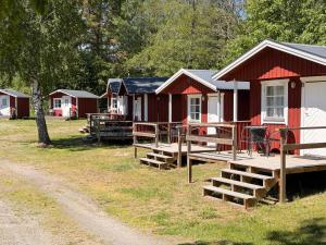 a row of red and white cabins in a park at Kapellskärs Camping och Vandrarhem in Aspnäs