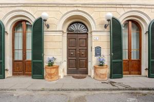 a building with green doors and two flower pots at House on the river in Calci