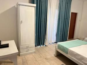 a bedroom with a bed and a dresser and green curtains at Nimro Luxury Residence in Ragama