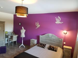 a bedroom with a purple wall with a bed and a table at Logis Hotel- Restaurant La Haie Des Vignes Séminaires et Evènementiel in Allain