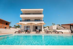 a house with a swimming pool in front of a building at Villa Amarea in Lopar