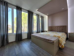 a bedroom with a bed and large windows at Vila Eva Lalz in Draç