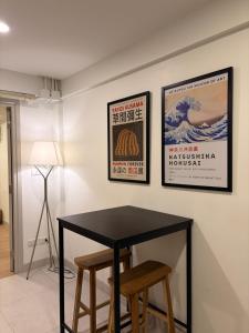 a black table with two stools in a room with two posters at 2 Bed & 2 Bath Suite, 2nd floor in Ban Bang Toei (1)