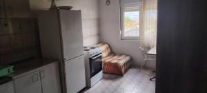 a kitchen with a refrigerator and a chair and a window at stan in Podgorica