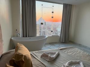 a bathroom with a bath tub and a large window at Pyramids gardens guest House in ‘Ezbet `Abd el-Ḥamîd