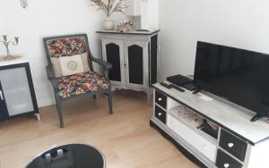 a living room with a flat screen tv and a chair at Le Petit Montceaux in Le Val-Saint-Père