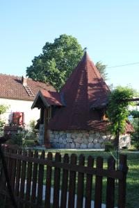 a house with a pointed roof behind a fence at Seosko domaćinstvo Peković in Danilovgrad