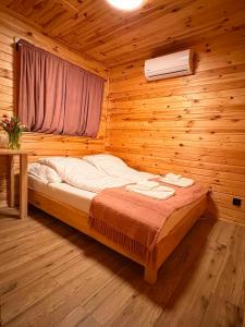 a bed in a wooden room with a window at Sigła w sidłach in Aleksandrów