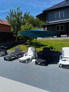 a group of lawn chairs and an umbrella at Vila Ali in Krivoglavci