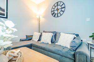 a living room with a blue couch and a clock on the wall at Gabriel's Gaff in Maidstone