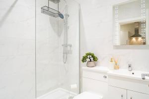 a white bathroom with a shower and a sink at Gabriel's Gaff in Maidstone