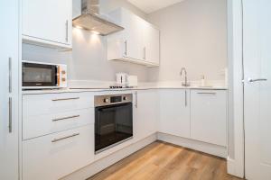 a white kitchen with white cabinets and a microwave at Gabriel's Gaff in Maidstone