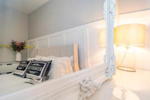 a white bedroom with a bed with a mirror at Gabriel's Gaff in Maidstone