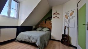 a bedroom with a bed and a guitar in it at La Parenthèse by CHERDECOUVERTE in Sambin
