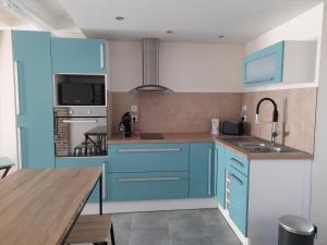 a kitchen with blue cabinets and a wooden table at Le lit de la SEINE in Saint-Seine-lʼAbbaye