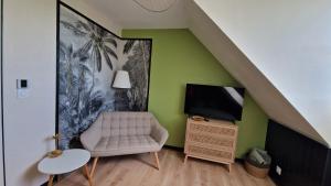 a living room with a chair and a television at La Parenthèse by CHERDECOUVERTE in Sambin