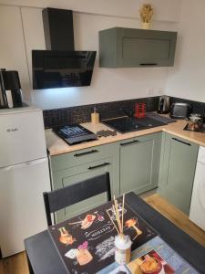 a kitchen with green cabinets and a table and a table and a tableablish at Elegant studio Hyper center in Rodez