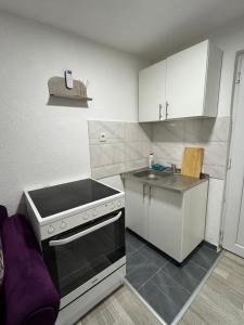 a small kitchen with a stove and a sink at Georgeous lux apartment # purple in Foča