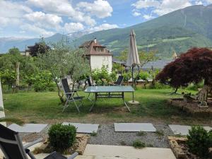 eine Terrasse mit Tisch, Sonnenschirm und Stühlen in der Unterkunft Garni Schuster in Corzes