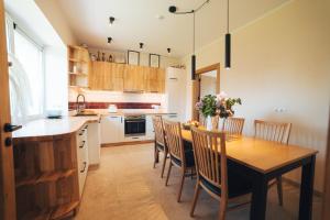 a kitchen with a wooden table and chairs at MADARAS Country house in Ventava