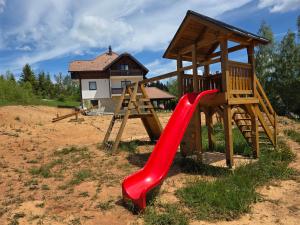 a playground with a red slide and a house at Apartmani Suncani breg Tara in Mitrovac