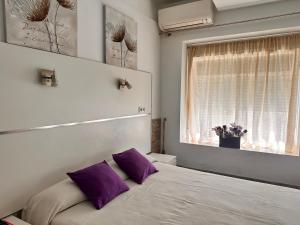 a bedroom with a bed with purple pillows and a window at Apartaments IRI in Pineda de Mar
