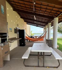 an outdoor patio with a hammock and a table at Casa Com 2 Quartos Barra Serinhaem - BA in Ituberá