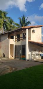 a white house with palm trees in front of it at Casa Com 2 Quartos Barra Serinhaem - BA in Ituberá