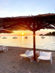 a group of chairs and an umbrella on a beach at Holiday House Zaton in Zaton
