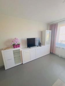 a living room with a tv on a white cabinet at Apartamenty na Pięknej 24-2 in Nowy Sącz