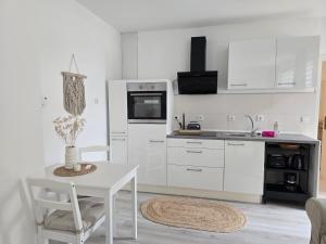 a kitchen with white cabinets and a white table and chairs at Lieblingsplatz Bevensen in Bad Bevensen