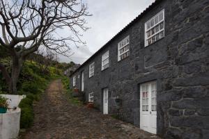 a stone house with white windows and a dirt road at Casa do Zé - AL in Manadas