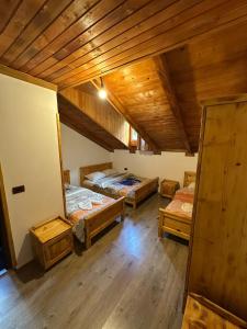three beds in a room with wooden ceilings at Natyra balcony in Valbonë