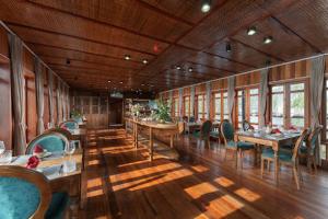 a dining room with tables and chairs and windows at Petit Prince Cruise in Cat Ba