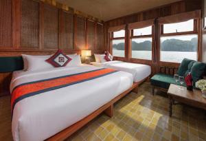 a bedroom with two beds and a couch and windows at Petit Prince Cruise in Cat Ba
