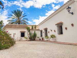 a white house with a palm tree in the background at Escuela La Crujía in Vélez-Málaga