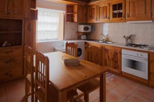 a kitchen with wooden cabinets and a wooden table and chairs at Casa do Zé - AL in Manadas