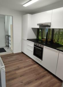 a kitchen with white cabinets and a wooden floor at Modernes City-Apartement - 6 Gäste in Weingarten