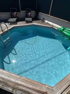 a large swimming pool with two chairs in it at La Parenthèse Gîte in Créhange
