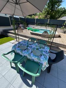 a table and chairs with an umbrella next to a pool at La Parenthèse Gîte in Créhange