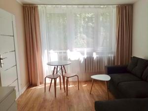 a living room with a couch and two tables in front of a window at Cichy Kącik in Wadowice