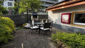 a patio with a table and chairs and a grill at Le Chalet de la Coudre in Neuchâtel