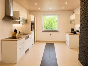 a kitchen with white cabinets and a window at PrimeLoft Apartments am Kurpark in Braunlage
